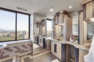 Kitchen with plenty of natural light, light stone countertops, recessed lighting, and a wall of windows