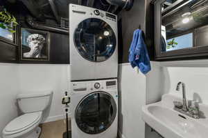 Laundry room featuring estacked washer and dryer, tile walls, and wainscoting