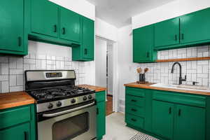 Kitchen featuring butcher block counters, stainless steel gas range, tasteful backsplash, and open shelves