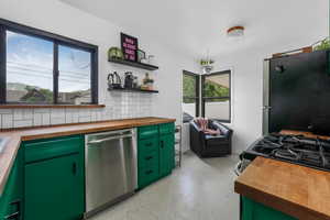 Kitchen with stainless steel appliances, wooden counters, dark aggregate flooring, and open shelves