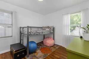 Bedroom with wood finished floors and multiple windows