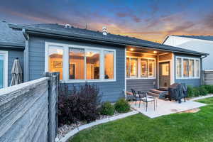 Rear view of house with a patio area and a shingled roof