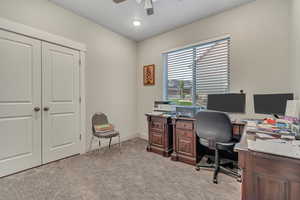 Home office featuring ceiling fan, light carpet, and baseboards