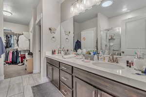 Full bath featuring double vanity, a stall shower, and a walk in closet