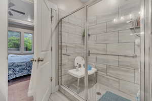Ensuite bathroom featuring a shower stall, ceiling fan, and ornamental molding