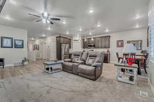Living room with ceiling fan, light wood-style flooring, baseboards, recessed lighting, and a textured ceiling