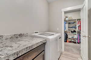 Laundry room featuring washing machine and dryer and light wood finished floors