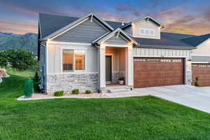 View of front of property featuring board and batten siding, an attached garage, a shingled roof, and driveway