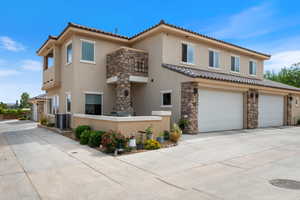 View of front of property featuring stucco siding, stone siding, a tiled roof, driveway, and a garage