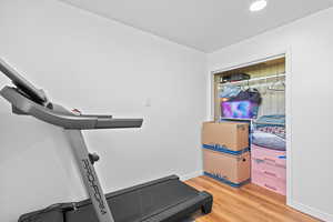 Workout area featuring light wood-style floors and recessed lighting