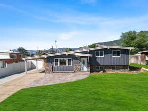 Tri-level home featuring a mountain view, an attached carport, board and batten siding, concrete driveway, and stone siding