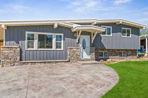 View of front of house with a front yard, board and batten siding, and a patio area