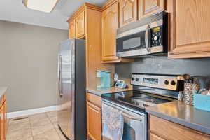Kitchen with stainless steel appliances, light tile patterned floors, and light brown cabinets