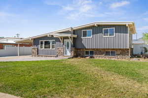 Split level home with board and batten siding, stone siding, and a patio