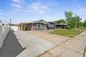 View of front of house with concrete driveway, stone siding, and an attached carport