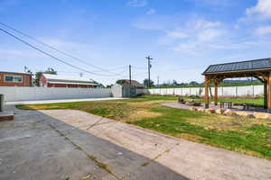 Fenced backyard with a gazebo, a fire pit, a patio area, and a storage shed