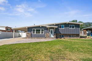 View of front of property featuring a carport, concrete driveway, a patio, stone siding, and board and batten siding
