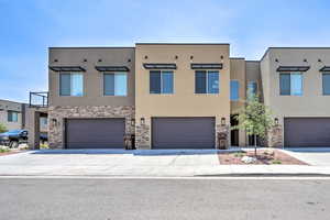 View of property featuring stucco siding, stone siding, and an attached garage