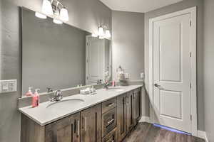Full bath with double vanity, wood finished floors, and baseboards