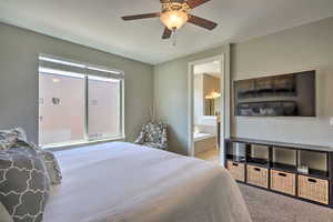 Bedroom featuring a ceiling fan, ensuite bath, and carpet flooring