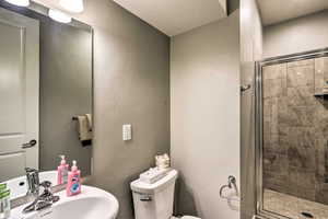 Bathroom featuring toilet, a stall shower, and a sink