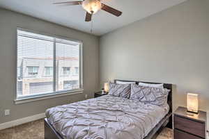 Carpeted bedroom featuring multiple windows, baseboards, and a ceiling fan