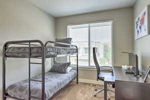 Bedroom featuring carpet floors, baseboards, and a desk