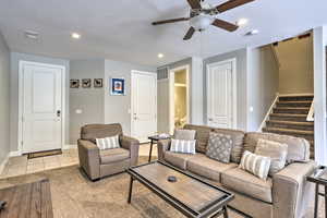 Living room featuring stairs, baseboards, ceiling fan, a textured ceiling, and recessed lighting