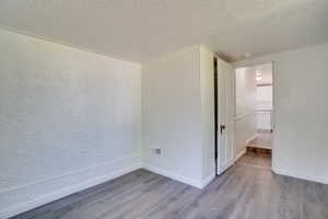 Empty room featuring wood finished floors, an ornate ceiling, and a smoke detector