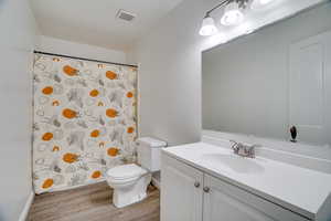 Full bath with wood finished floors, vanity, and curtained shower
