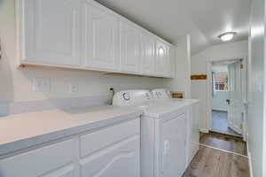 Laundry room featuring dark wood-style floors, independent washer and dryer, and cabinet space