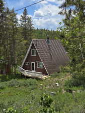 View of home's exterior with a deck and a view of trees