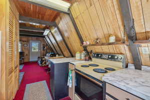 Kitchen with white electric range, carpet flooring, wooden walls, lofted ceiling, and wood ceiling