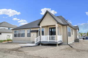View of front facade featuring stucco siding, a deck, and roof with shingles
