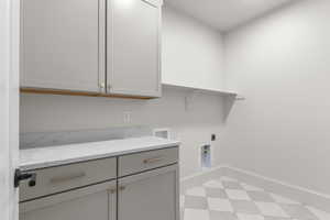 Washroom featuring cabinet space, hookup for a washing machine, light floors, and hookup for an electric dryer