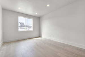 Empty room with recessed lighting, light wood-style floors, and a textured ceiling
