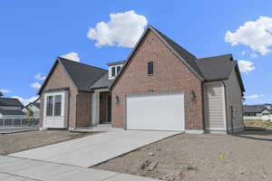 View of front facade with concrete driveway, brick siding, and a shingled roof