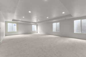 Unfurnished room featuring a tray ceiling, plenty of natural light, carpet floors, recessed lighting, and a textured ceiling