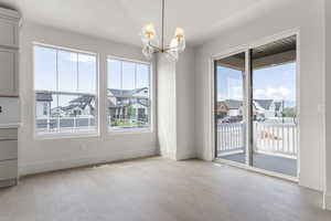 Unfurnished dining area featuring a residential view, light wood finished floors, and a chandelier