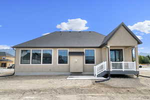 Back of house featuring a mountain view, stucco siding, roof with shingles, and a patio area