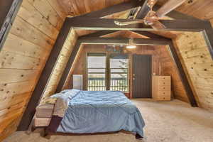 Bedroom with wood ceiling, wood walls, carpet flooring, and access to exterior
