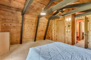 Carpeted bedroom with wooden walls and wooden ceiling