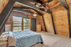 Carpeted bedroom with wooden walls and wood ceiling