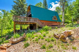 Back of property featuring a metal roof, a wooden deck, stairs, and a gambrel roof