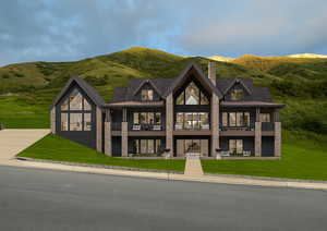 View of front of property with a balcony, a chimney, a front yard, and a mountain view