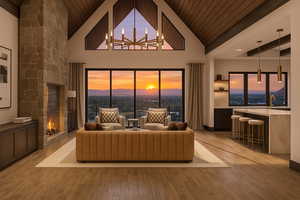 Living room featuring a fireplace, wood ceiling, a chandelier, light wood-type flooring, and high vaulted ceiling
