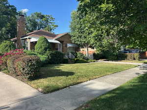 View of front of home featuring a front lawn, brick siding, and a chimney