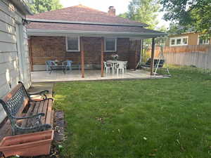 Back of house featuring brick siding, a chimney, roof with shingles, and a patio area