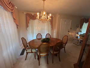Dining area featuring a chandelier and light colored carpet