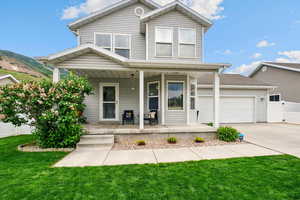 Traditional-style house with covered porch, driveway, and an attached garage